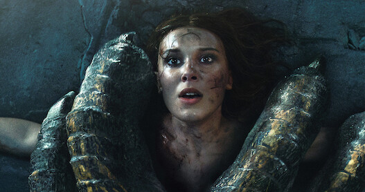 Millie Bobby Brown as Princess Elodie in distress in a forest.