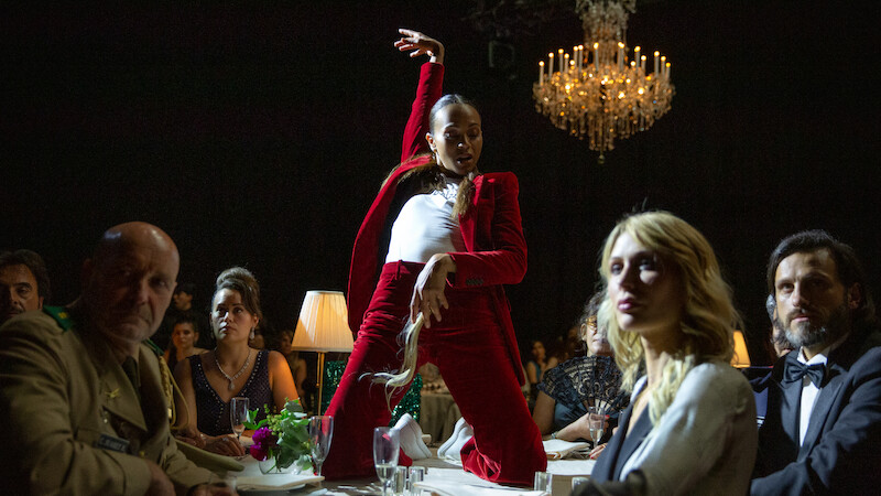 Zoe Saldaña strikes a pose on top of a table while performing the standout song from the film, "El Mal."