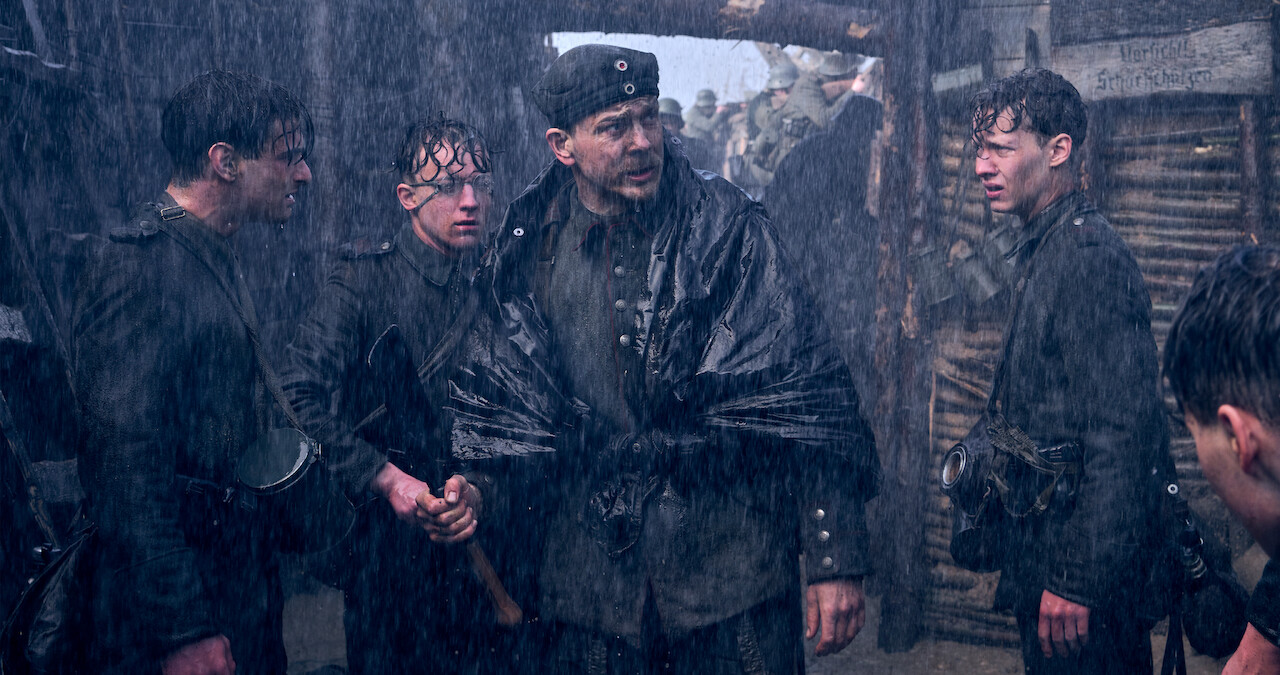 Soldiers standing in the rainy trenches in All Quiet on the Western Front.