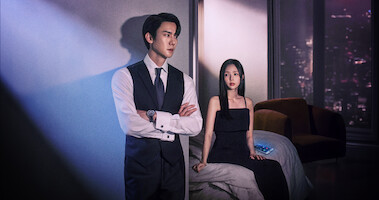 Yoo Yeon-seok and Chae Soo-bin stand next to each other in a high-rise apartment wearing black dinner attire in an image from the series ‘When the Phone Rings.’