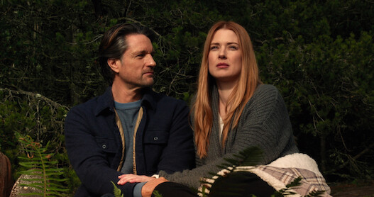 Two people sitting down next to each other outside
