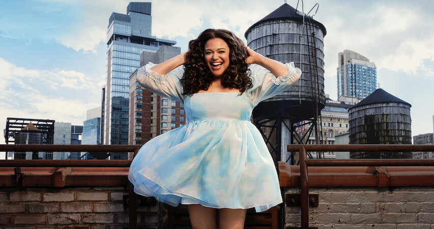 Michelle Buteau wears a bright, blue dress jacket and laughs.