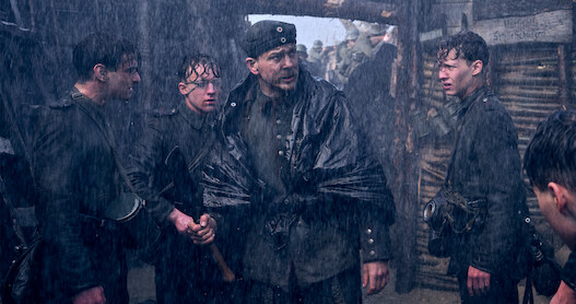 Soldiers standing in the rainy trenches in All Quiet on the Western Front.
