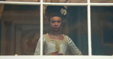 queen charlotte stands in front of a window thinking 