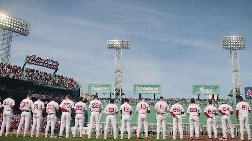 Boston Red Sox players lined up for the national anthem facing The Green Monster at Fenway Park