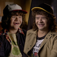 A split-screen image featuring a younger Gaten Matarazzo alongside an older teen version of him, both dressed in casual attire with baseball caps, smiling warmly in softly lit indoor settings.