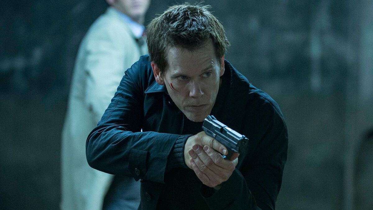 Kevin Bacon as Special Agent Ryan Hardy points a gun at a suspect in 'The Following.'