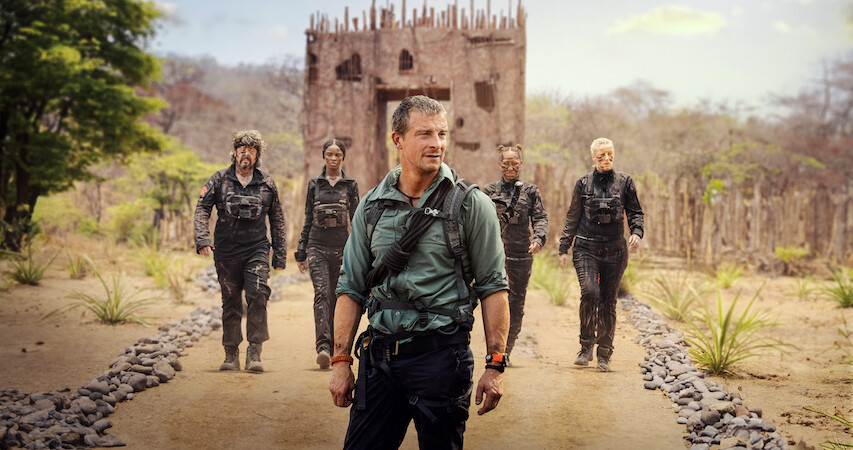 Bear Grylls stands in front of four people on a rocky path. 