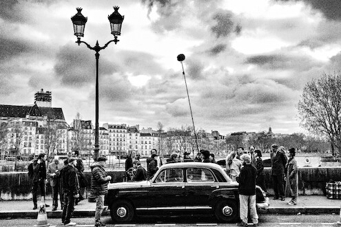 Cast and crew film Nouvelle Vague in the streets of Paris.
