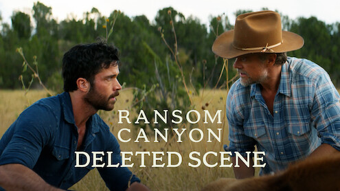 Two men in outdoor rural setting, Yancy Grey (Jack Schumacher) in a blue shirt and Staten Kirkland (Josh Duhamel) in a cowboy hat and plaid shirt, kneeling in tall grass, with trees in the background. Text reads: Ransom Canyon Deleted Scene.