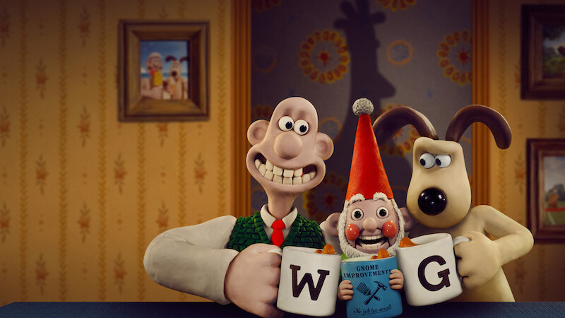 Wallace and Gromit clink mugs with a gnome sitting between then.
