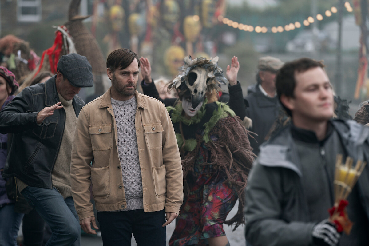 Will Forte as Gilbert Power walks through a crowd at a festival in 'Bodkin'