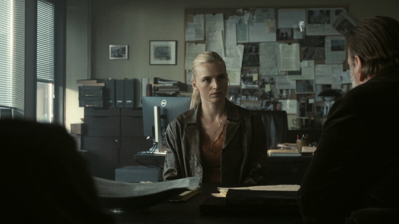 Clara Dessau as Tea sits at a police desk in 'The Night Asset.'