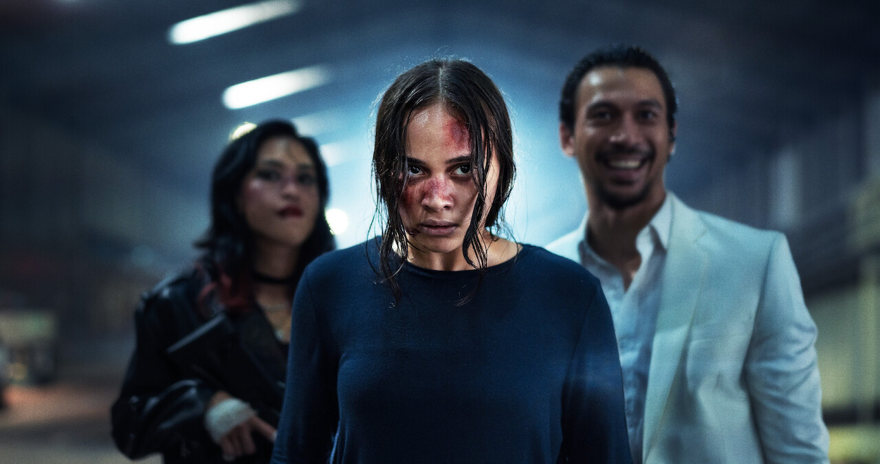 Aurora Ribero with blood on her face stands in front of two people in an image from 'The Shadow Strays.'