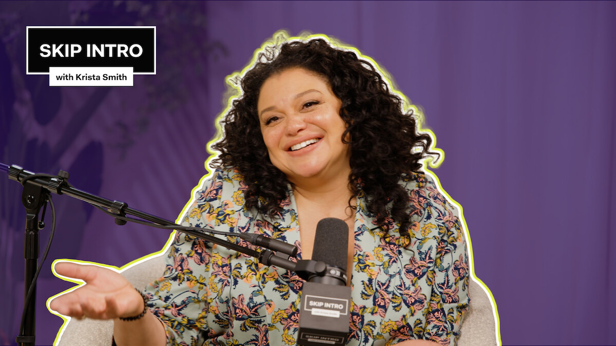 Michelle Buteau smiles and sits in front of a microphone, wearing a floral top. The background is purple, and there's a text box saying "SKIP INTRO with Krista Smith" in the top left corner.