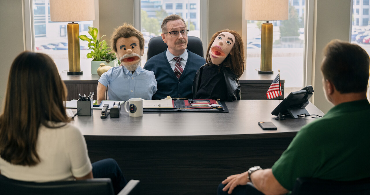 Scott Thompson as Dr. Louis Pfeffer in FUBAR Season 1 holds puppets.