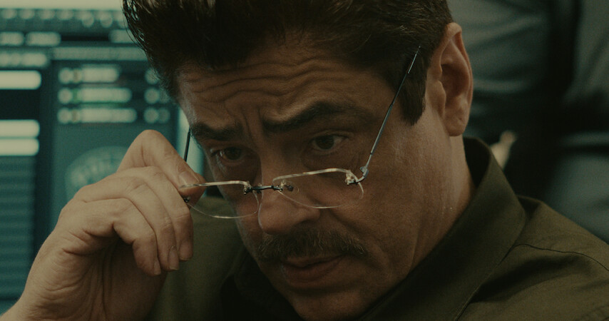 Benicio Del Toro lowers his eyeglasses in a still from 'Reptile.'
