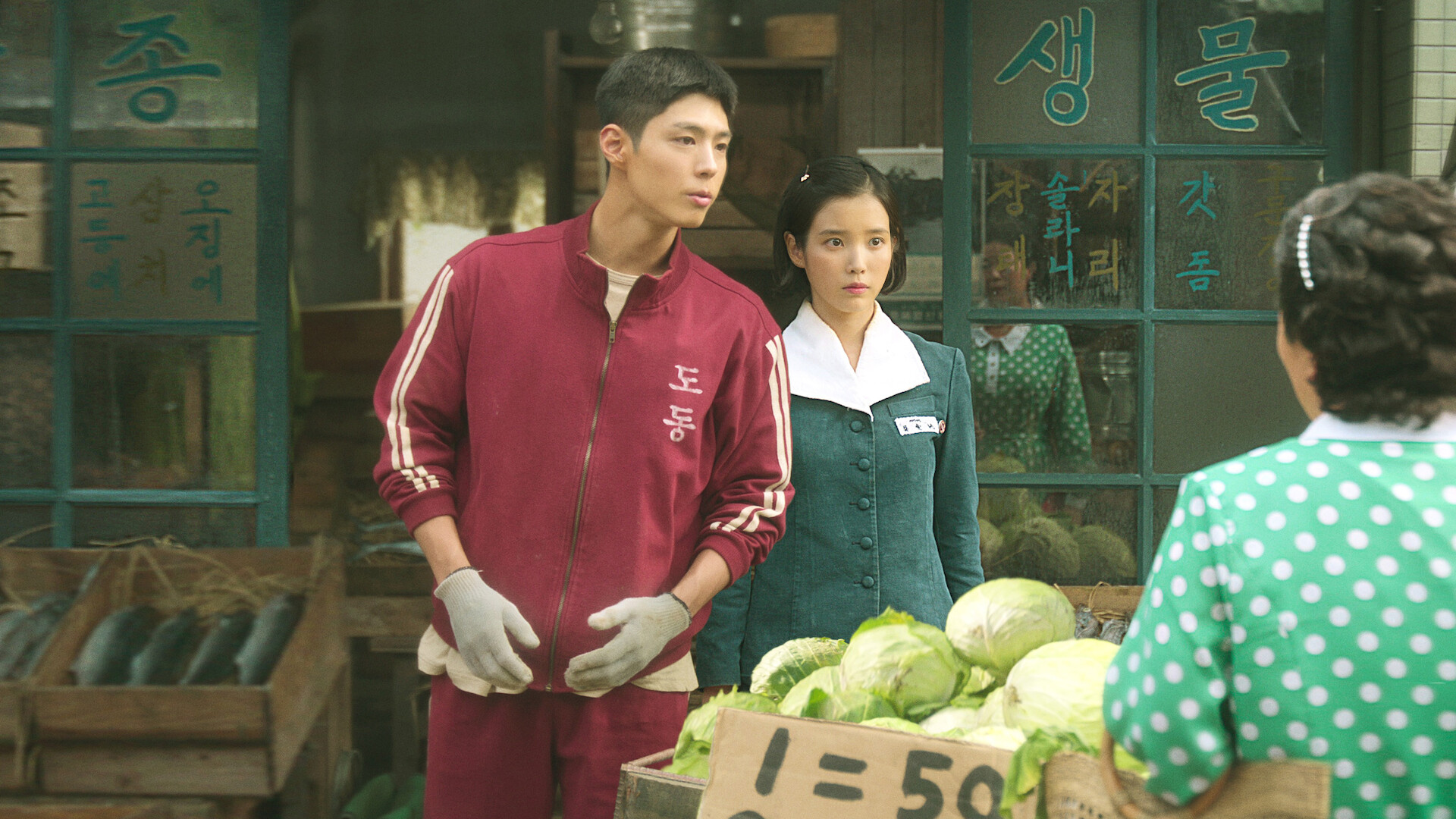 When Life Gives You Tangerines key art - A man in a green tracksuit and a woman stand at a vegetable stand