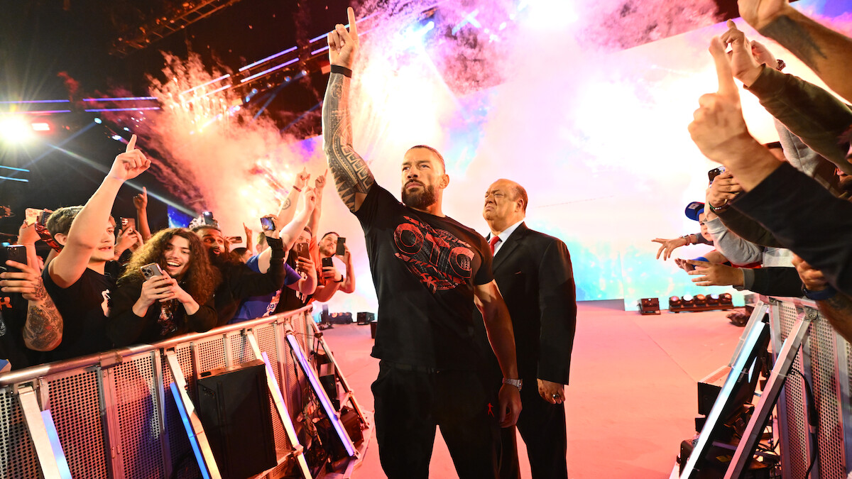Roman Reigns enters greeting the crowd with pyrotechnics going off behind him.