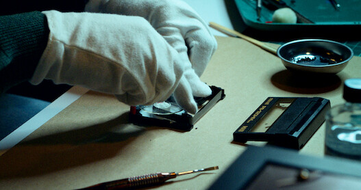A close up of a character's hands working to restore video footage.