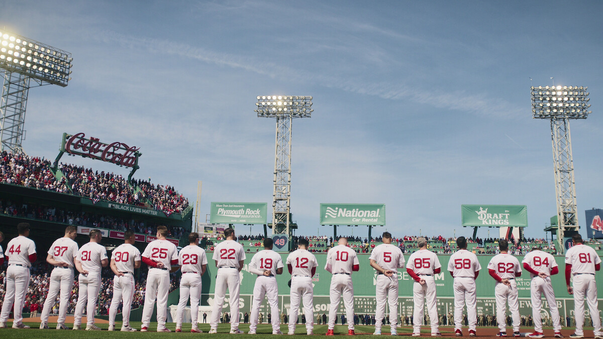 Boston Red Sox players lined up for the national anthem facing The Green Monster at Fenway Park