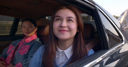 Kitty looks hopefully out of a car window next to Yuri