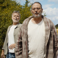Franck Dubosc, Jean Reno, Alizée Caugnies, Suzanne Clément, and Raphael Romand stand in an open field with trees and a hill behind them in an image from the film 'Family Pack.'