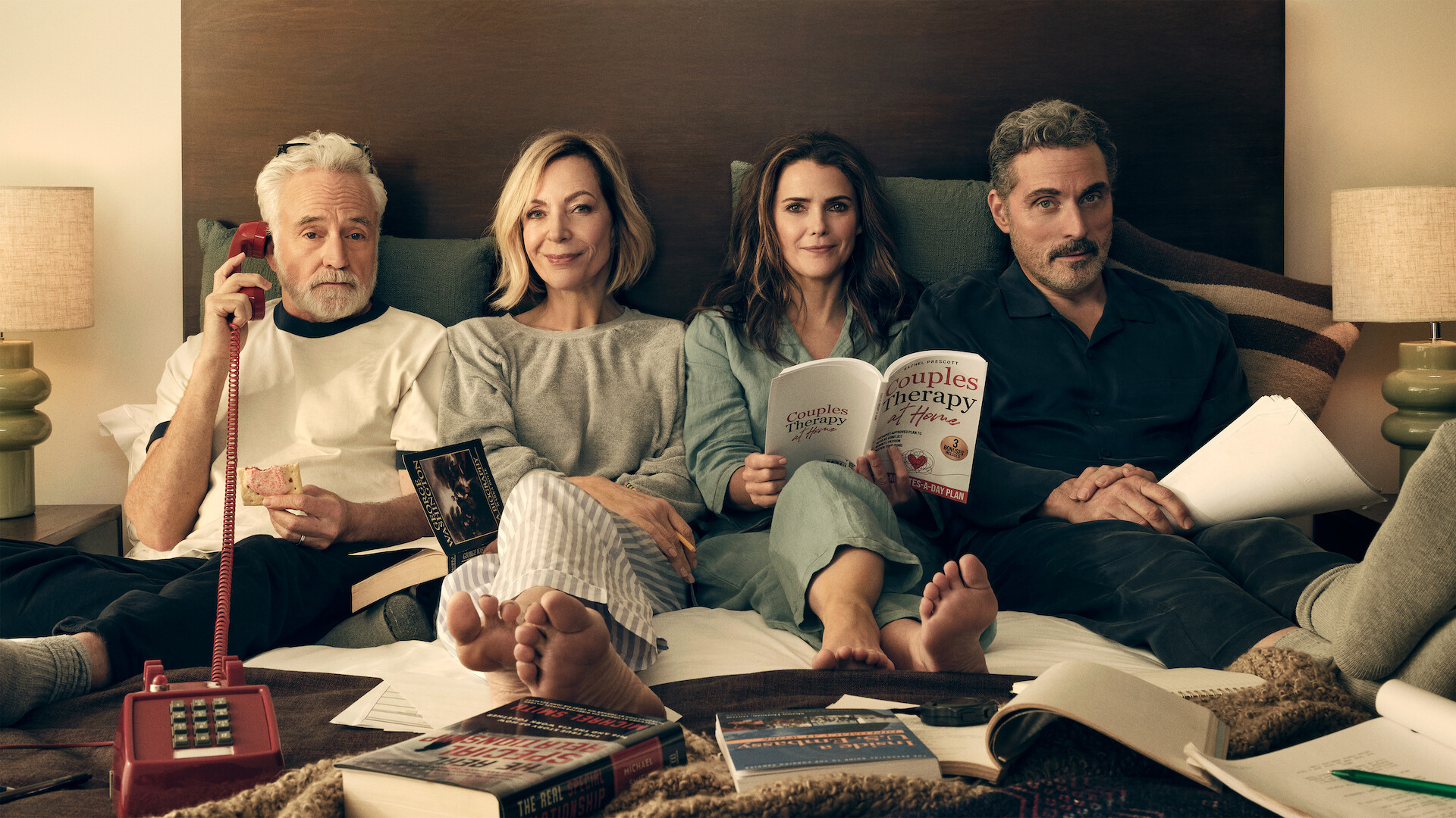 Keri Russell, Rufus Sewell, Allison Janney e Bradley Whitford deitados juntos em uma cama, usando pijamas.
