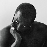 A black and white photo of Sean Combs staring at the vi with his head in his hands.