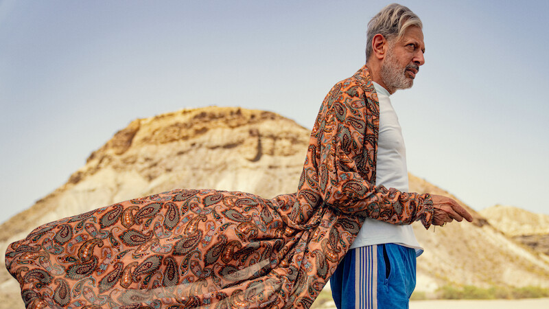 Jeff Goldblum as Zeus stands near a mountain wearing a long flowing robe and track pants in Season 1 of Kaos