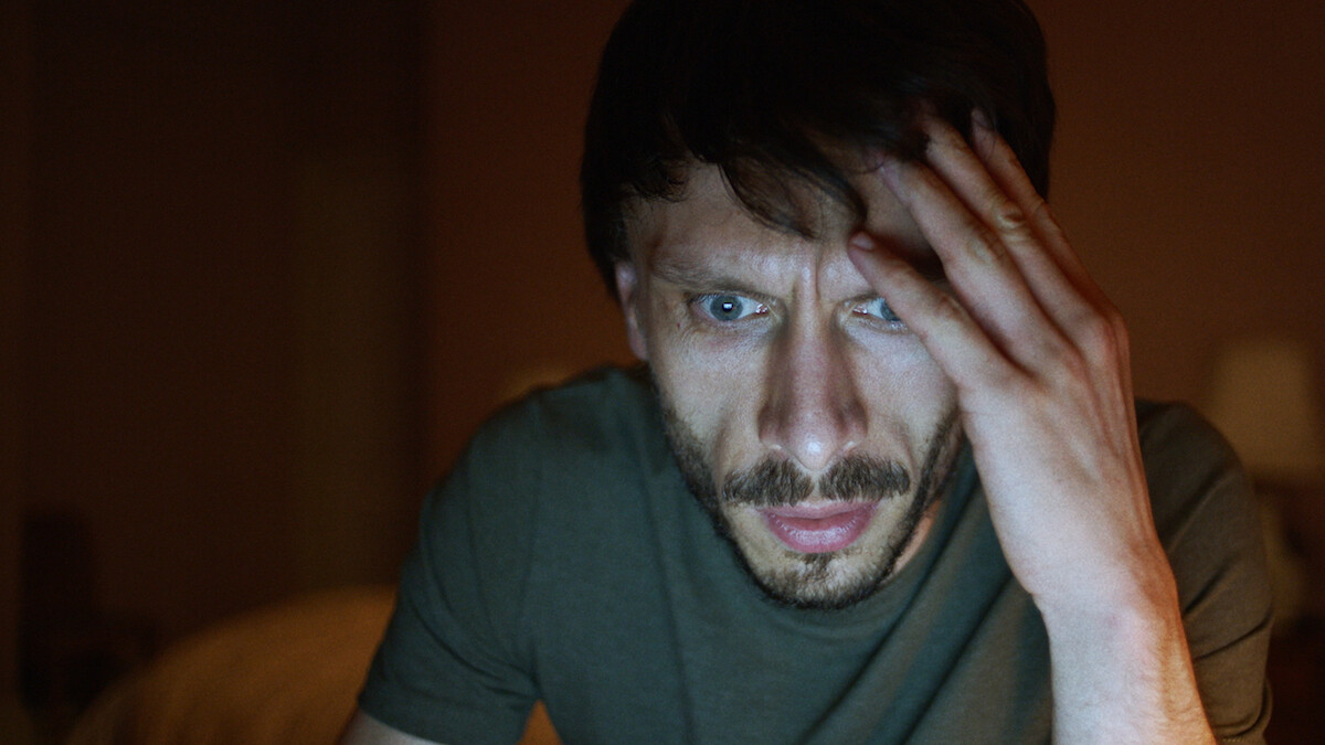 Richard Gadd shows an fearful expression while looking at a bright screen in season 1 of 'Baby Reindeer'