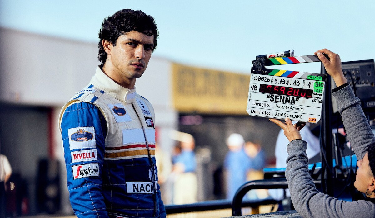 Ayrton Senna (Gabriel Leone) wears a white and blue racing suit behind the scenes of Senna.