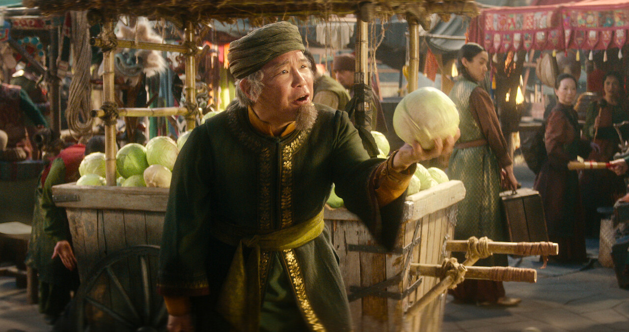 ames Sie as Cabbage Merchant holds a cabbage at a market in season 1 of 'Avatar: The Last Airbender'