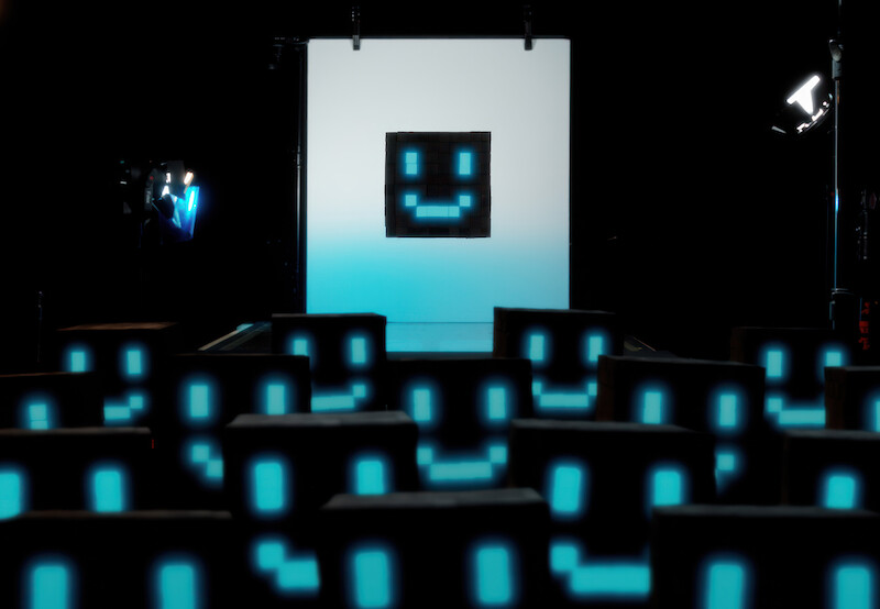 Imagem mostra várias representações de uma inteligência artificial, um cubo preto com olhos e boca luminosos