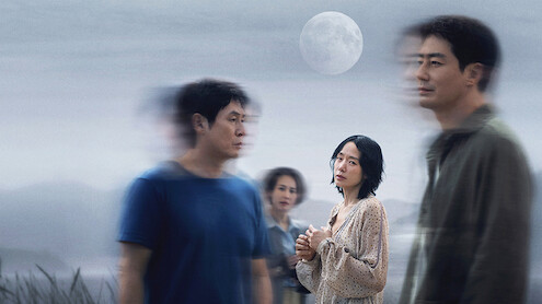 A woman stands in focus outdoors under a full moon, surrounded by three blurred people, with a calm, misty landscape in the background. The scene feels mysterious and contemplative.
