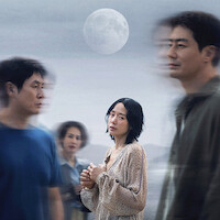 Woman in light dress stands pensively under a full moon, surrounded by blurred figures in a muted outdoor setting, evoking a sense of isolation or reflection.