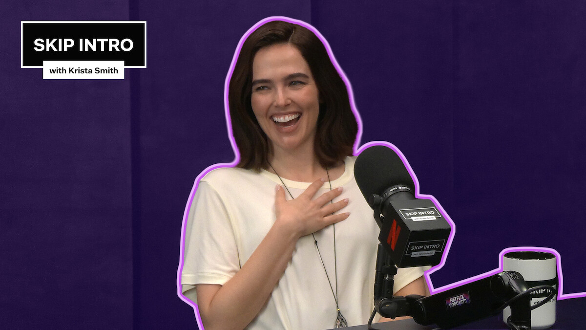 Zoey Deutch sits smiling and laughing in front of a microphone during a podcast recording for "Skip Intro with Krista Smith." The background is purple, and the podcast logo appears in the top left corner.