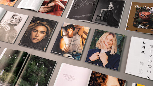 An overhead grid of Issue 25 covers and open spreads of the magazine on a warm gray background.