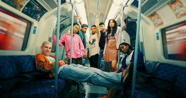 The cast of 'Everything Now S1' rides the London Underground together in Season 1 of 'Everything Now.'