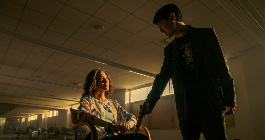 Michelle Yeoh as Mama Sun sitting in an empty room with an armed interrogator in 'The Brothers Sun.'