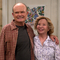 Kurtwood Smith as Red and Debra Jo Rupp as Kitty stand in their kitchen smiling in Part 2 of 'That '90s Show.'