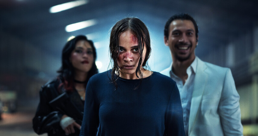 Aurora Ribero with blood on her face stands in front of two people in an image from 'The Shadow Strays.'