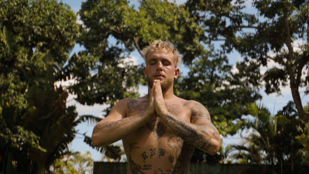 Jake Paul sitting shirtless with his hands clasped together. 