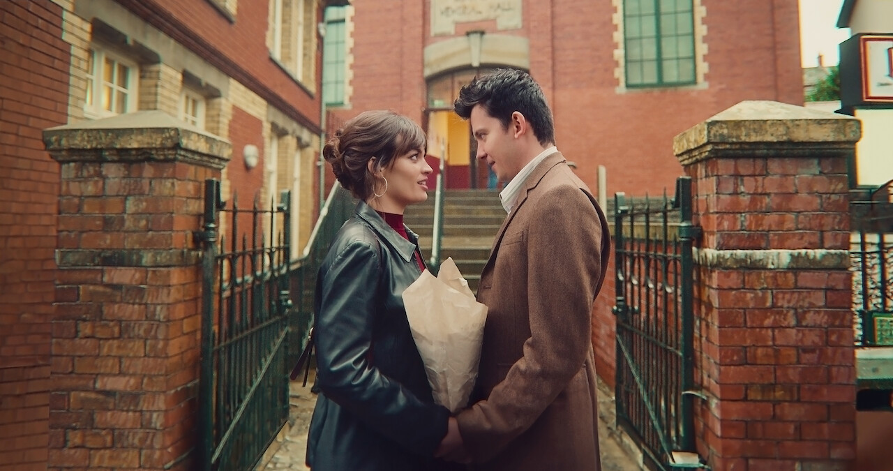 Emma Mackey as Maeve and Asa Butterfield as Otis stand facing each other and holding hands in Season 4 of 'Sex Education.'