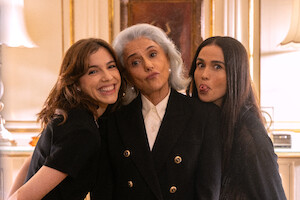 Três atrizes, Marieta Severo (branca, de cabelos grisalhos e vestindo terno preto sonbre camisa branca), Alice Wegmann (de cabelos curtos e castanhos, na altura do ombro, vestindo um vestido preto) e Nanda Costta (de cabelos longos e escuros, vestindo vestido preto) posam lado a lado em uma sala branca com adornos nas paredes