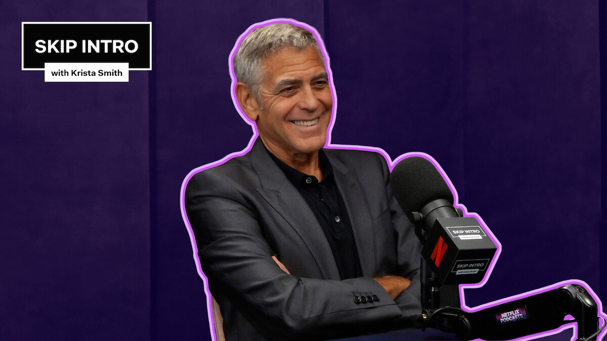 George Clooney sits smiling in front of a microphone during a podcast recording for "Skip Intro with Krista Smith." The background is purple, and the podcast logo appears in the top left corner.