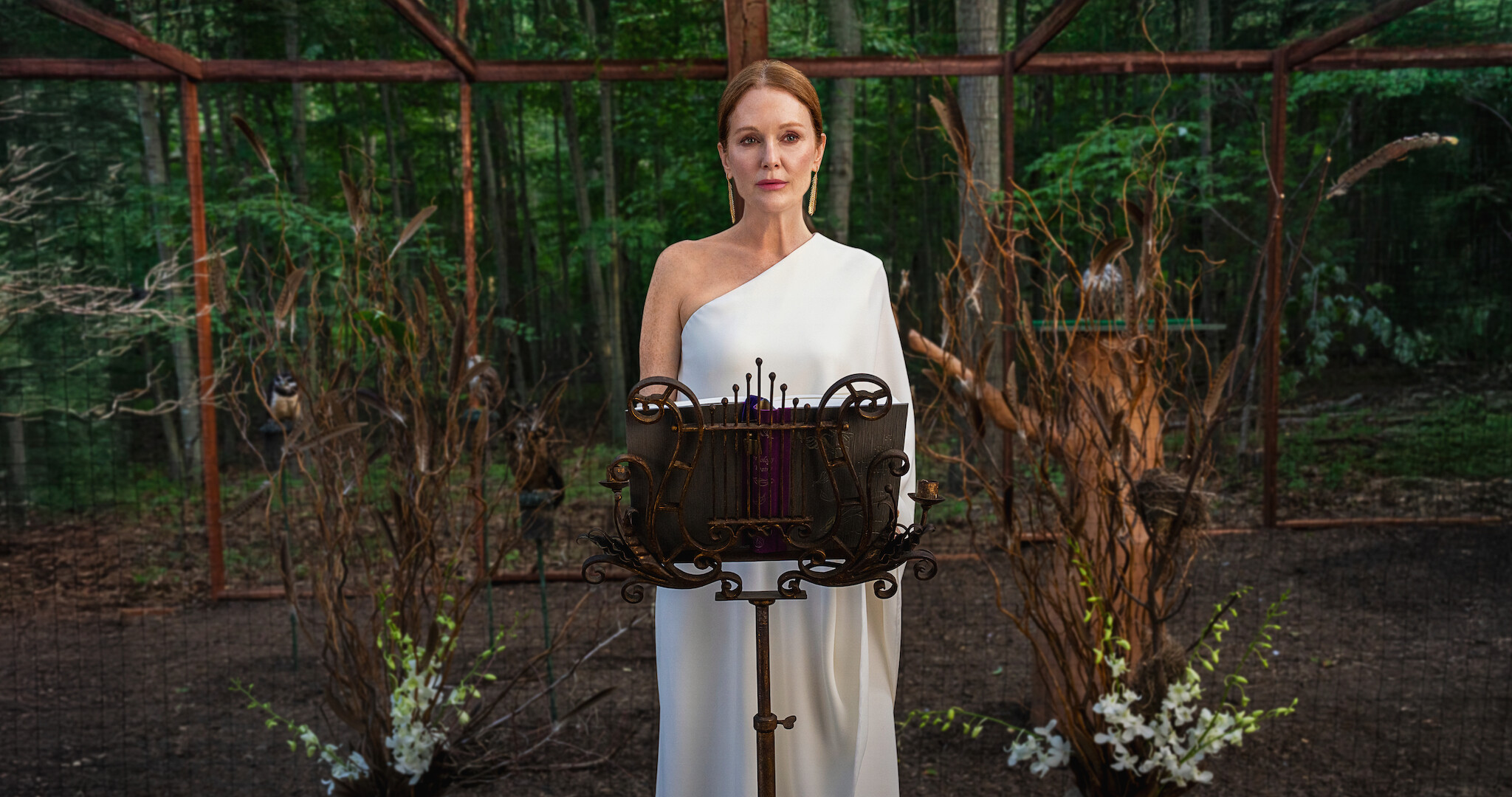 Sirens - Julianne Moore in a white dress standing at a podium. 