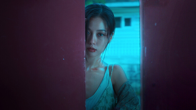 In a promotional still from the series 'The Frog,' Go Min-si holds a phone to her ear while soaking wet. The title 'The Frog' is superimposed on the image to the right of her.