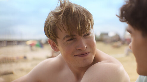 Kit Connor as Nick smiles on a beach in Season 3 of 'Heartstopper'