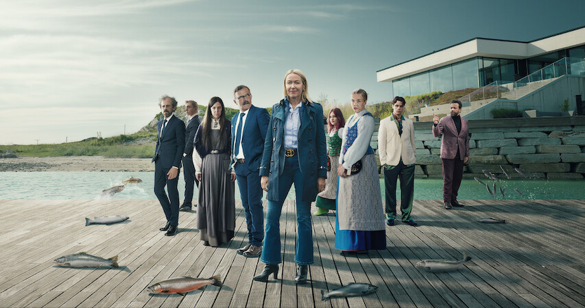 The cast of the series 'Billionaire Island' stand on a dock that's dotted with large fish.